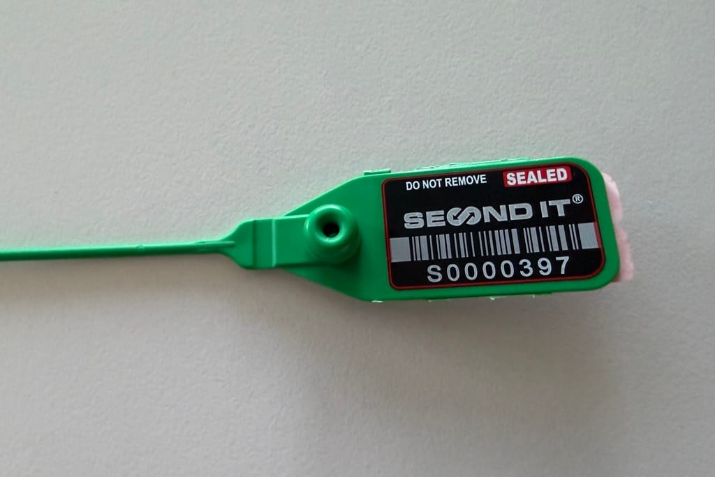 Zegel van Second IT: groene kunststof trekzegel met etiket ‘Sealed’, barcode en serienummer