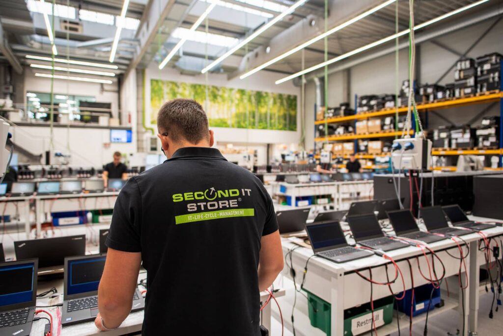 Technicien de reconditionnement à une ligne de diagnostic d’ordinateurs portables, vu de dos